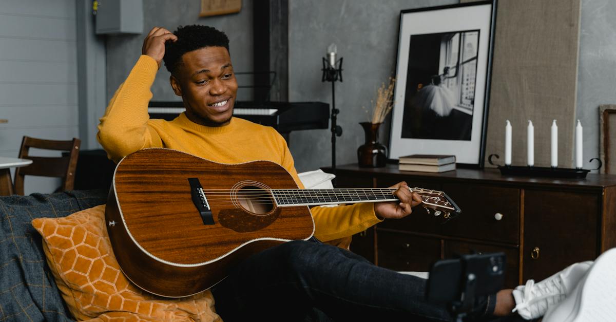 a-man-holding-a-guitar-sitting-on-a-couch-6554507