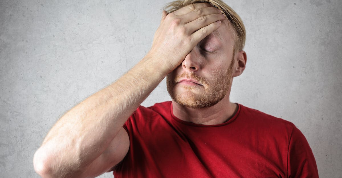 a-man-in-red-shirt-covering-his-face-8112212