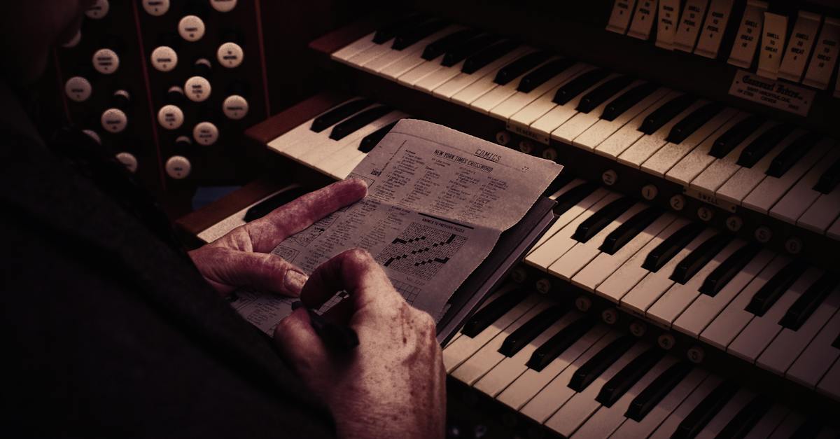 a-person-sitting-in-front-of-piano-holding-gray-newspaper-1020317