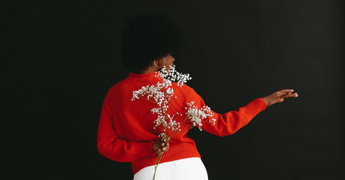 back-view-of-sensual-black-woman-in-white-denim-and-white-red-sweater-holding-gypsophila-flower-behi-3818553