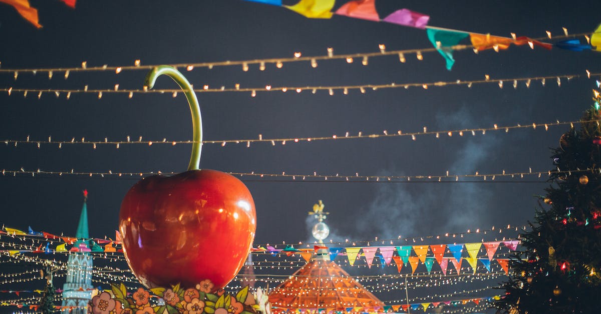 big-red-glossy-toy-apple-on-roof-of-building-on-fairground-against-dark-sky-in-evening-city-park-dec-2370812