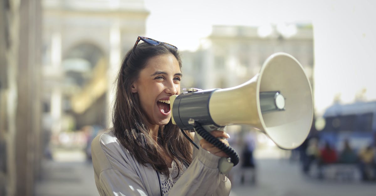 cheerful-young-woman-screaming-into-megaphone-8709655