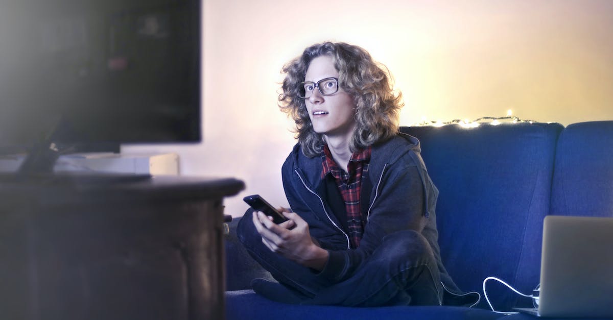 concentrated-male-with-long-hair-sitting-on-comfortable-sofa-at-home-and-messaging-on-social-media-v-1278886