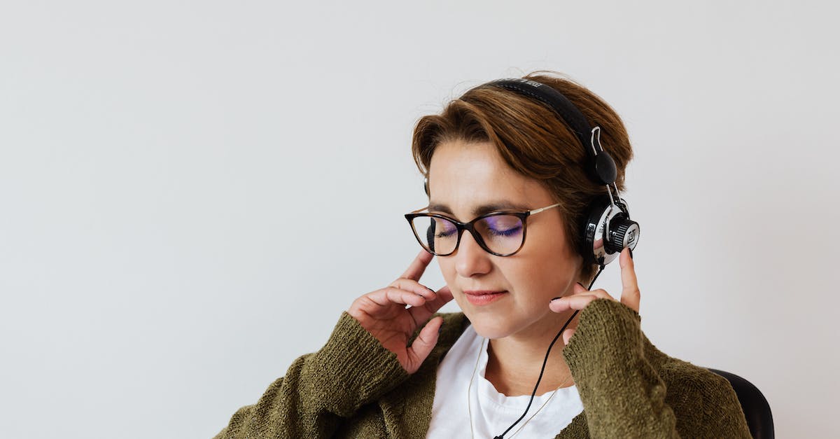 content-glad-female-wearing-eyeglasses-and-headphones-listening-to-good-music-and-touching-headset-w-2650378