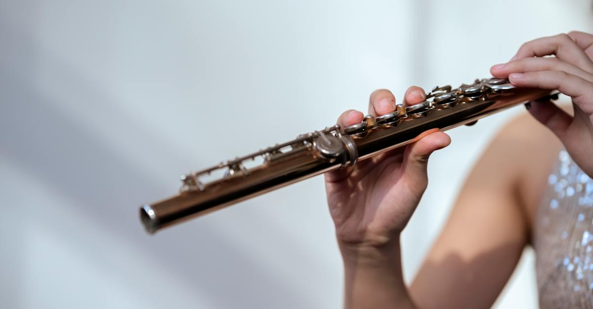 crop-unrecognizable-female-musician-in-glittering-dress-with-bare-shoulder-playing-flute-on-white-ba-2330629