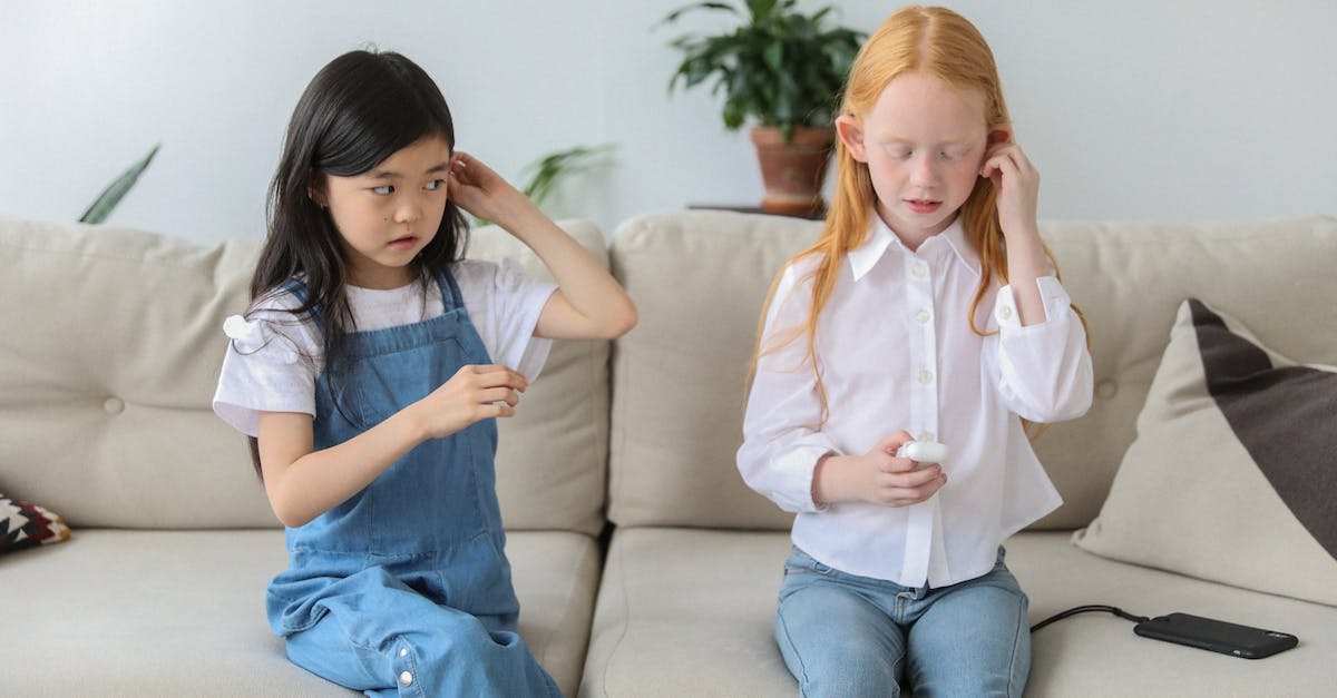 curious-multiracial-children-listening-to-music-in-tws-earphones-while-sitting-on-couch-at-home-2603914