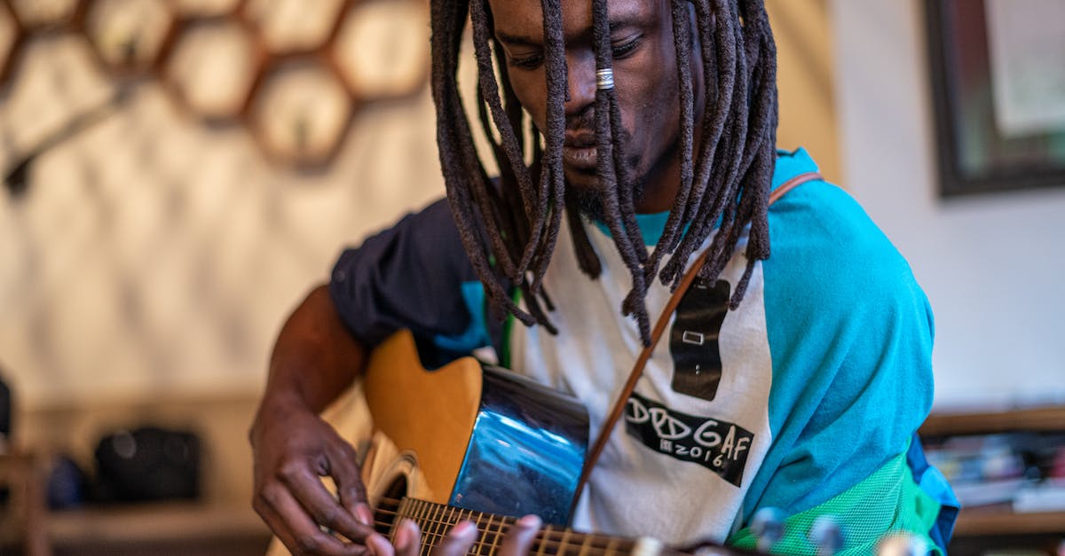 focused-black-man-playing-guitar-in-studio-1365121