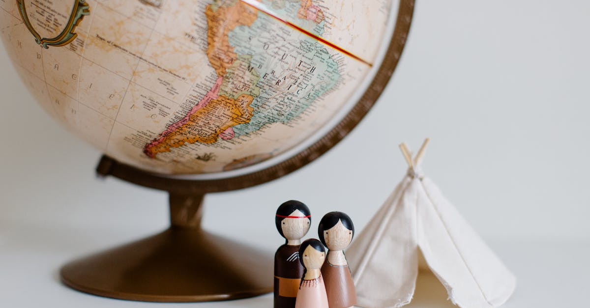 from-above-of-miniature-toys-tipi-house-and-american-indian-family-placed-near-vintage-globe-against-3967224