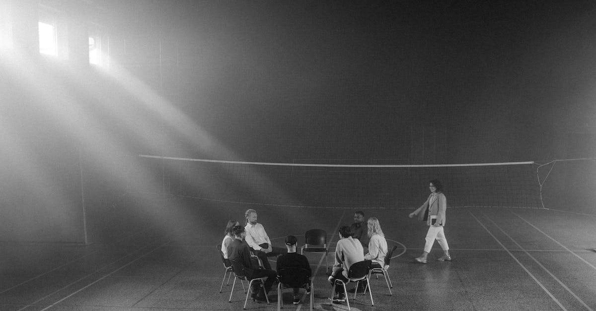 grayscale-photo-of-people-sitting-on-the-chairs-5561594