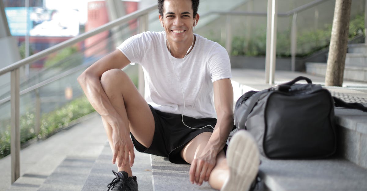 happy-young-african-american-male-athlete-listening-to-music-and-resting-after-training-on-stairs-on-8585017