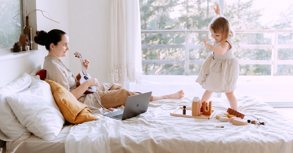 happy-young-woman-playing-ukulele-for-daughter-at-home-5182391