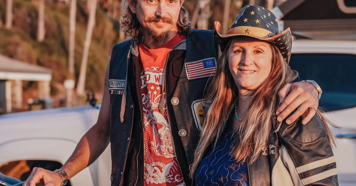 man-in-brown-hat-and-blue-denim-jacket-standing-beside-woman-in-red-and-white-floral-8114120