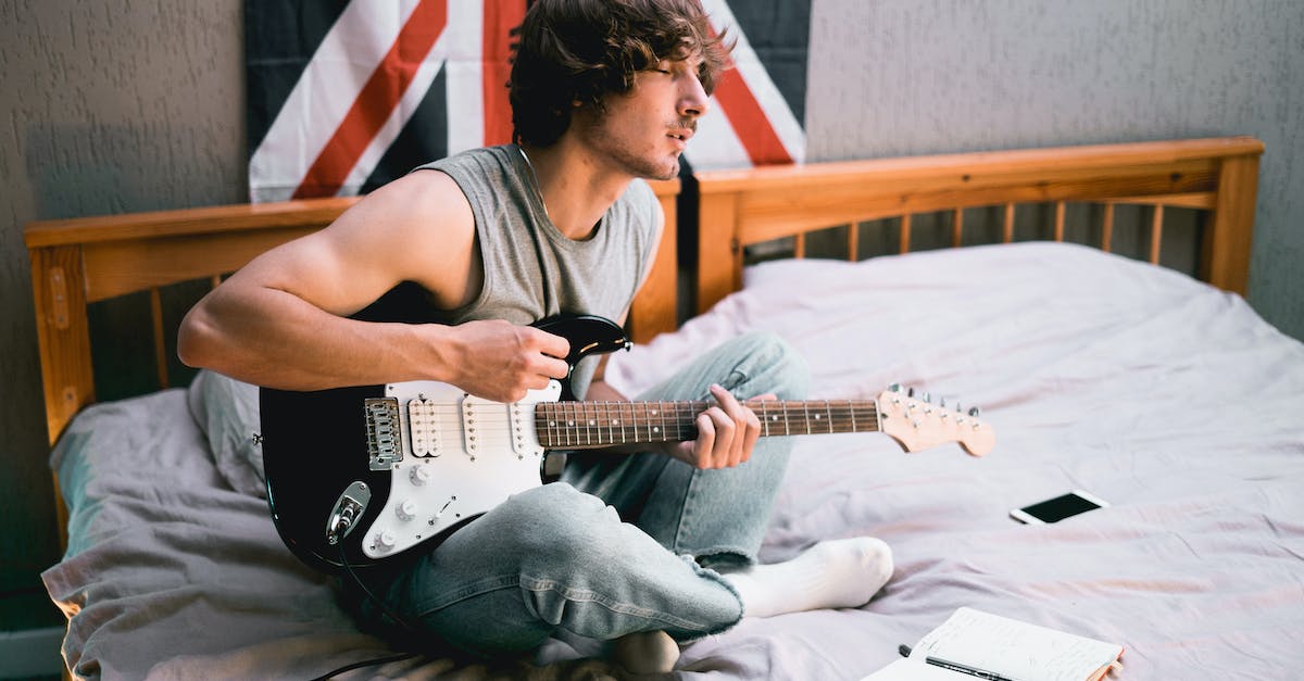 man-in-gray-tank-top-playing-electric-guitar-8174106