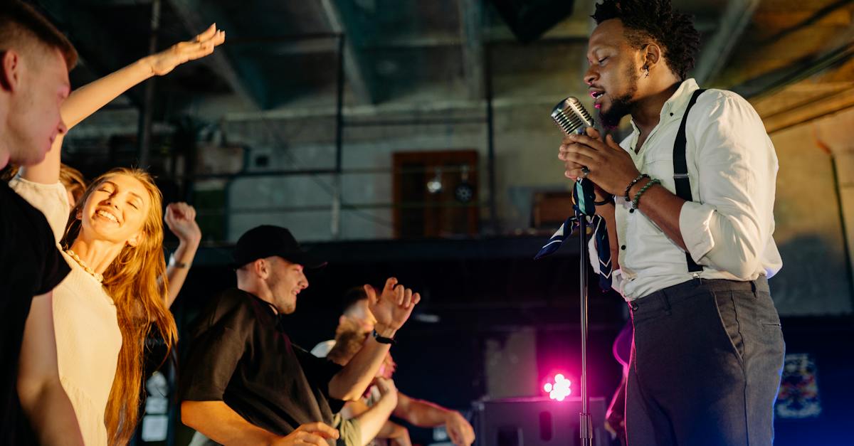 man-in-white-shirt-singing-on-stage-in-front-of-people-2880286