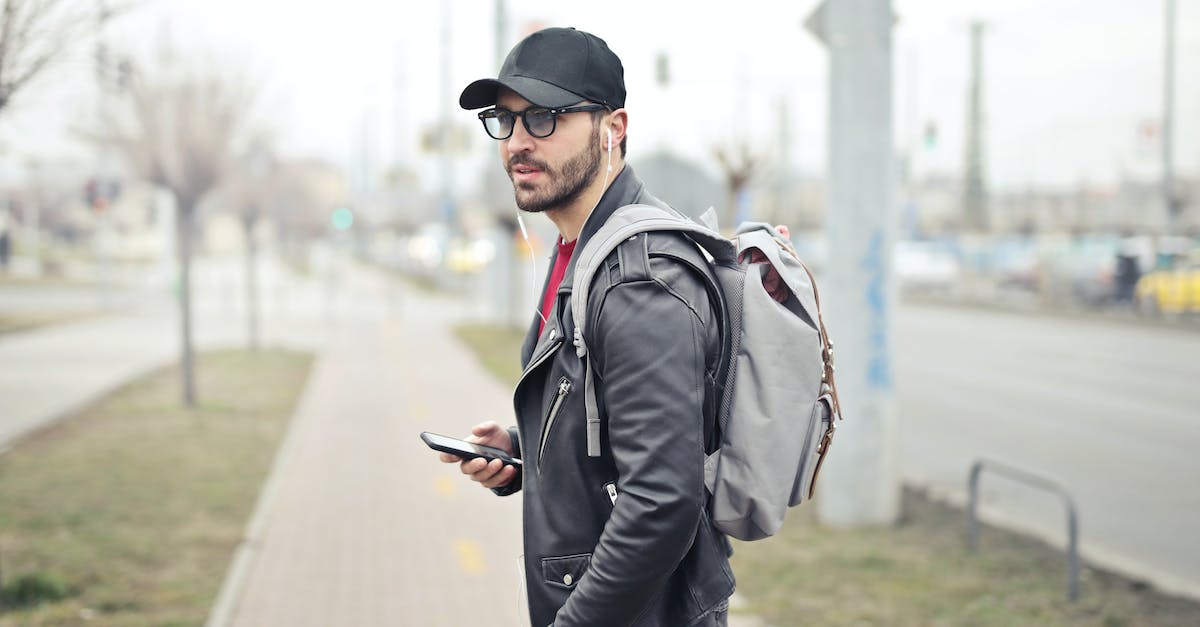 man-wearing-black-leather-jacket-holding-smartphone-4615934