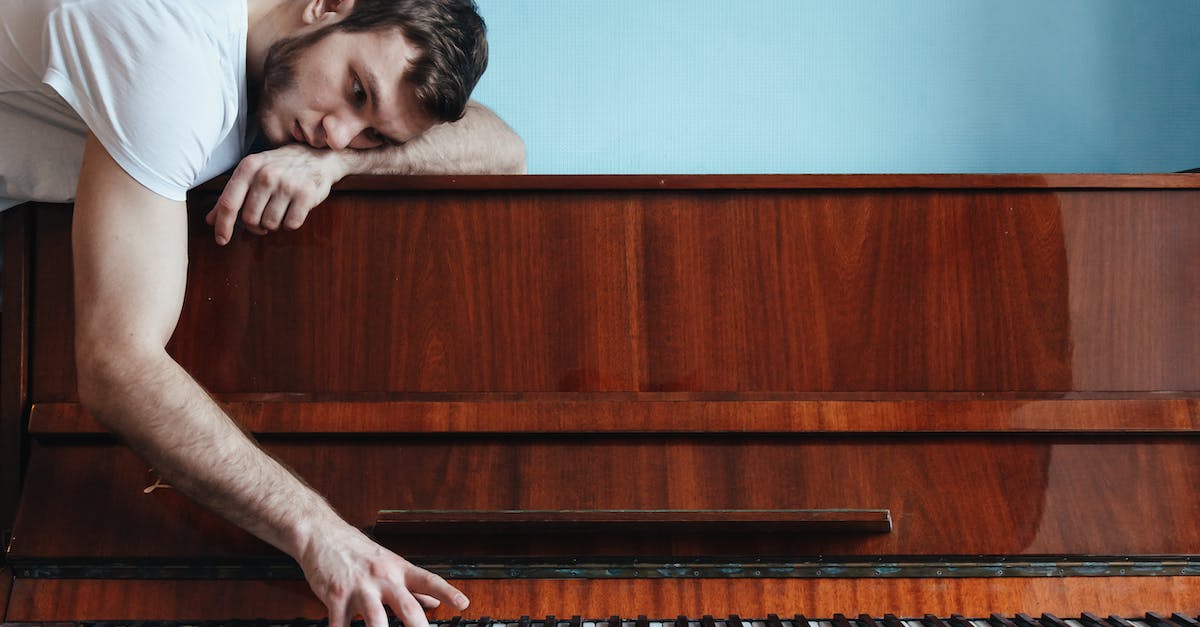 melancholic-pianist-playing-piano-near-blue-wall-4344685