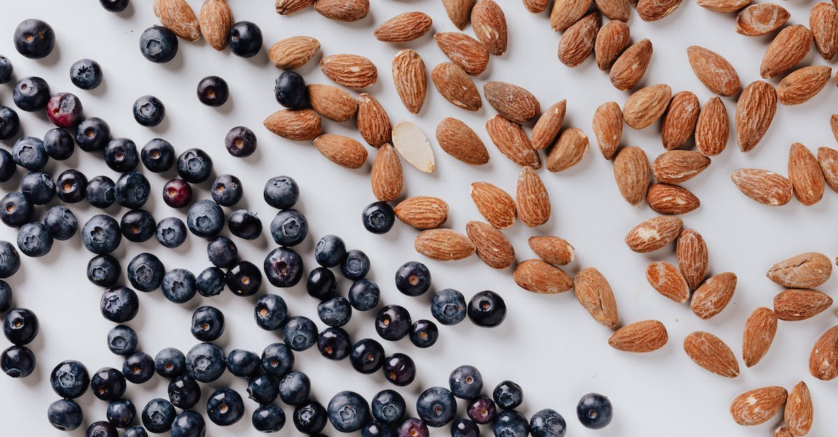 raw-almonds-and-fresh-blueberries-put-on-white-surface-9381124