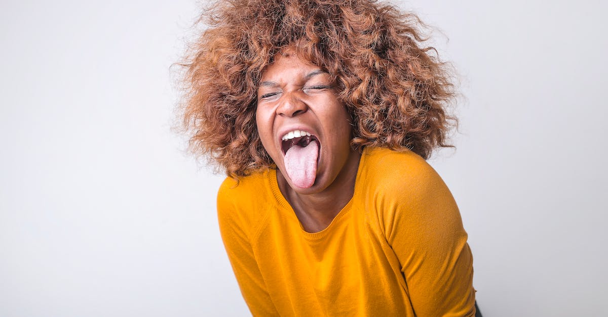 red-haired-african-american-female-in-vivid-yellow-sweater-standing-with-eyes-closed-and-tongue-out-1160034