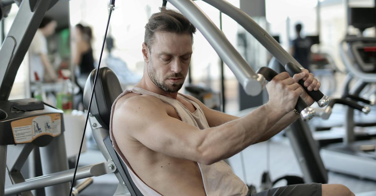 side-view-of-confident-muscular-man-doing-exercises-on-shoulder-press-machine-while-training-in-mode-1975950