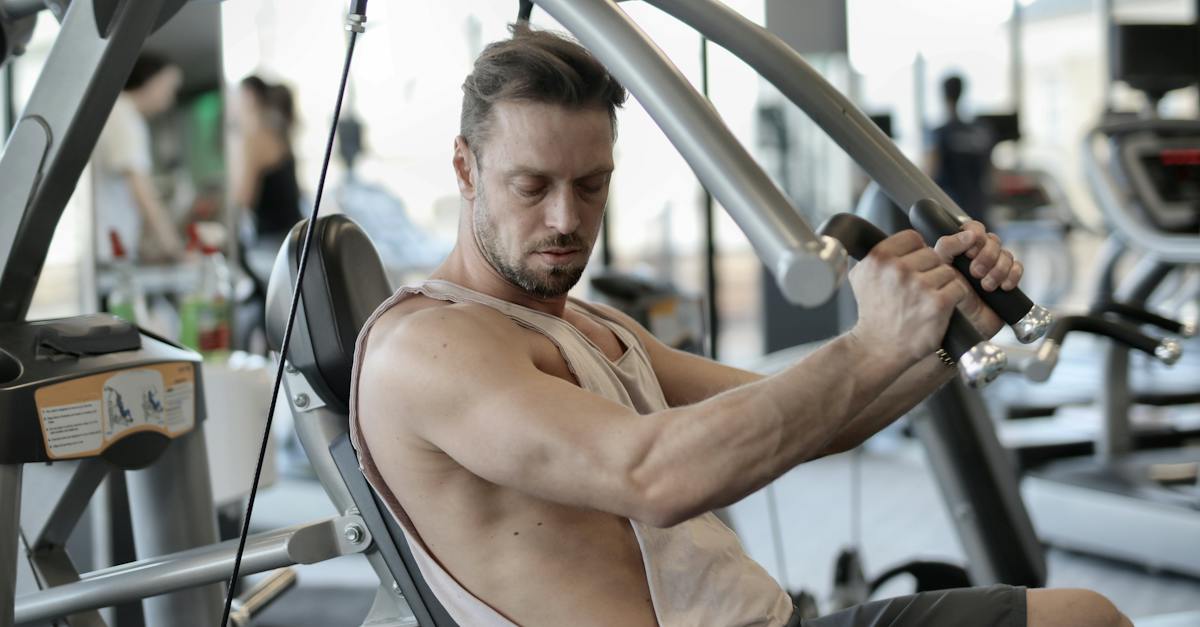 side-view-of-confident-muscular-man-doing-exercises-on-shoulder-press-machine-while-training-in-mode-2512479