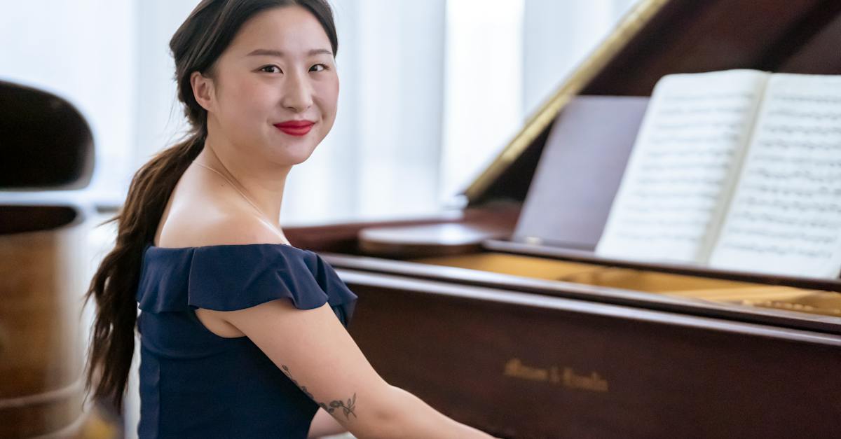 side-view-of-positive-asian-female-pianist-in-elegant-dress-pressing-piano-keys-while-practicing-sym-7470588