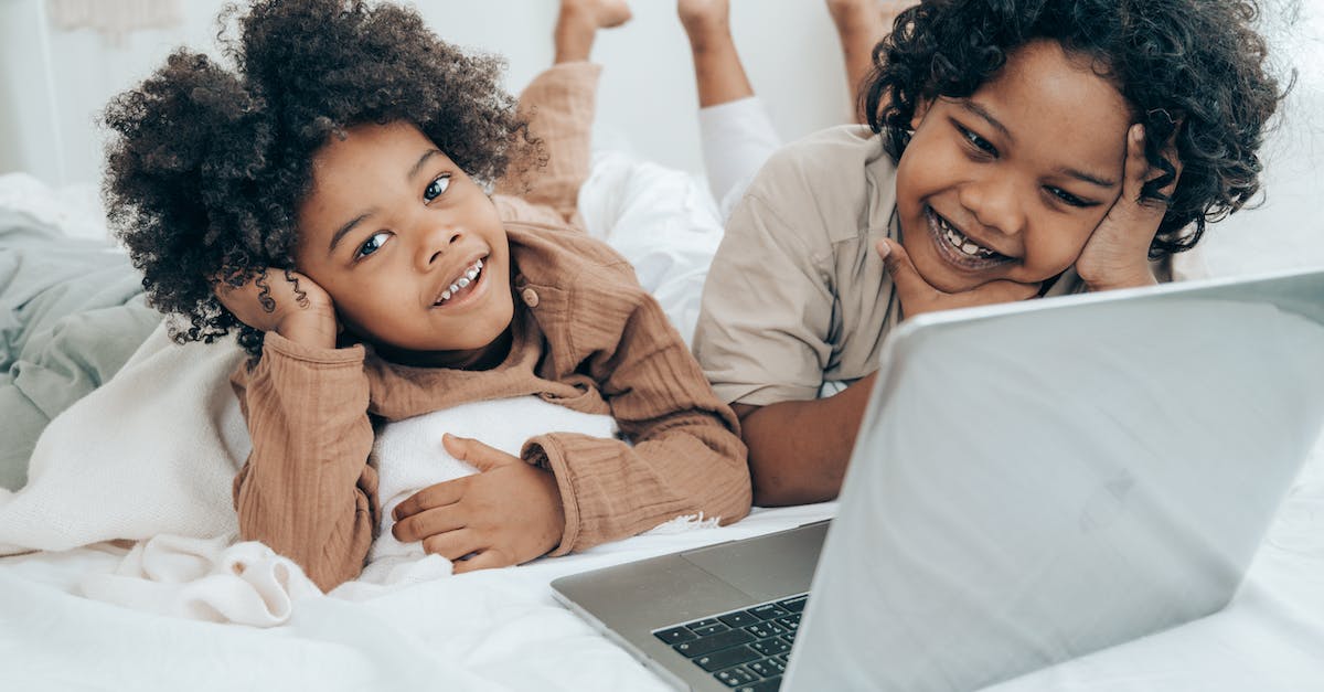 smiley-black-boys-watching-funny-video-on-laptop-on-bed-3285869