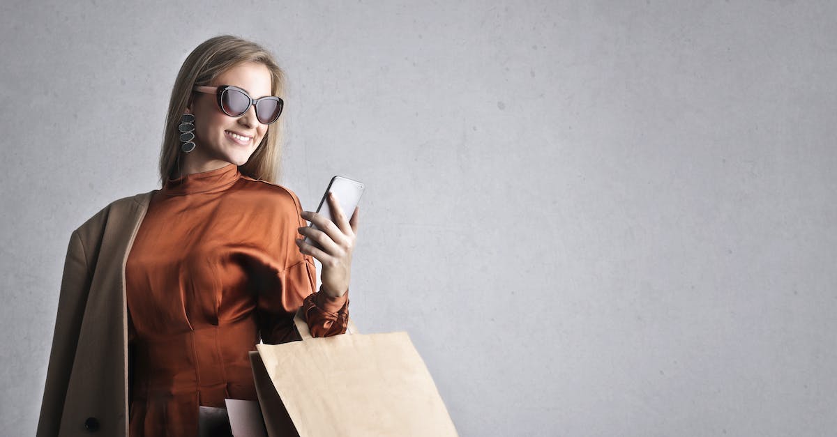 smiling-female-in-trendy-wear-and-stylish-sunglasses-standing-with-paper-shopping-bags-on-background-8005077