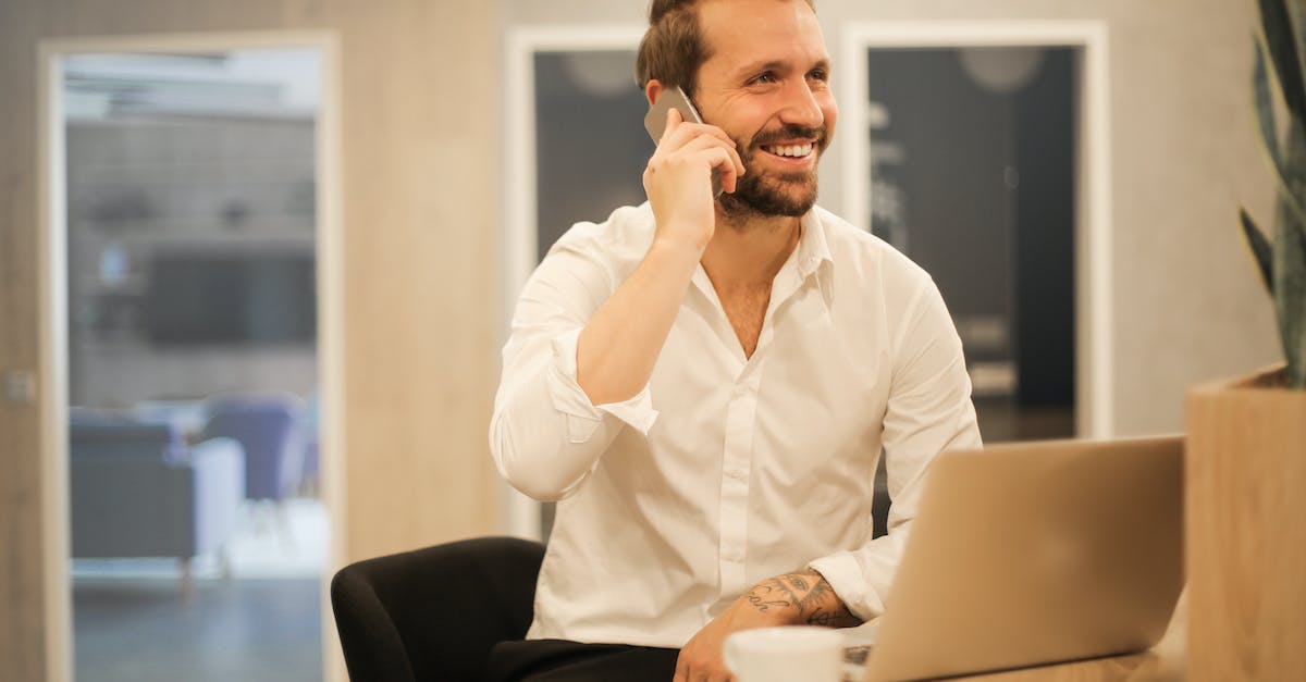 smiling-formal-male-with-laptop-chatting-via-phone-5231987