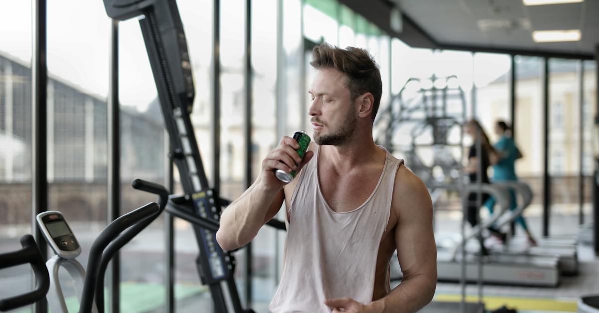 strong-young-sportsman-drinking-energy-drink-during-break-in-workout-in-modern-gym-4869032