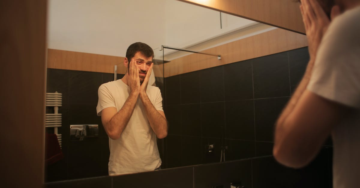 tired-man-looking-in-mirror-in-bathroom-7383619