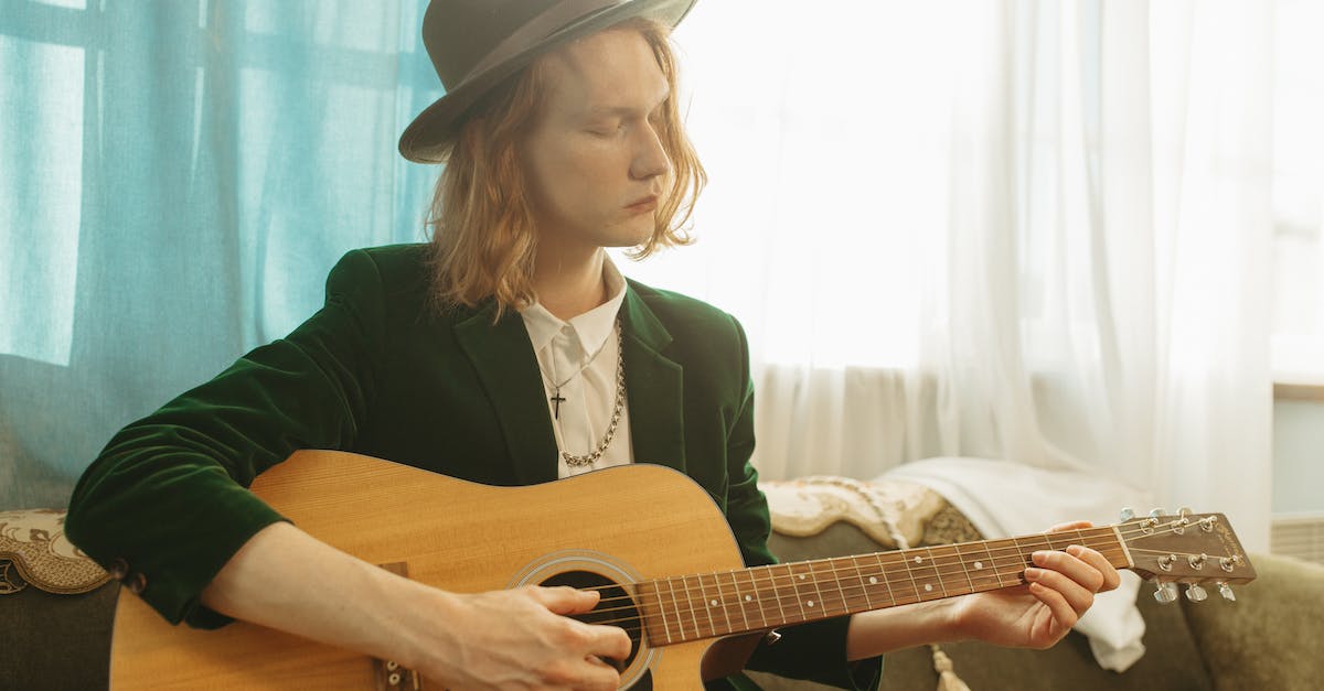 woman-in-black-blazer-playing-brown-acoustic-guitar-1541114