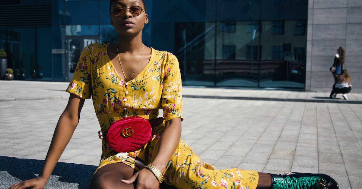 woman-in-yellow-floral-jumpsuit-sitting-on-concrete-floor-8543524