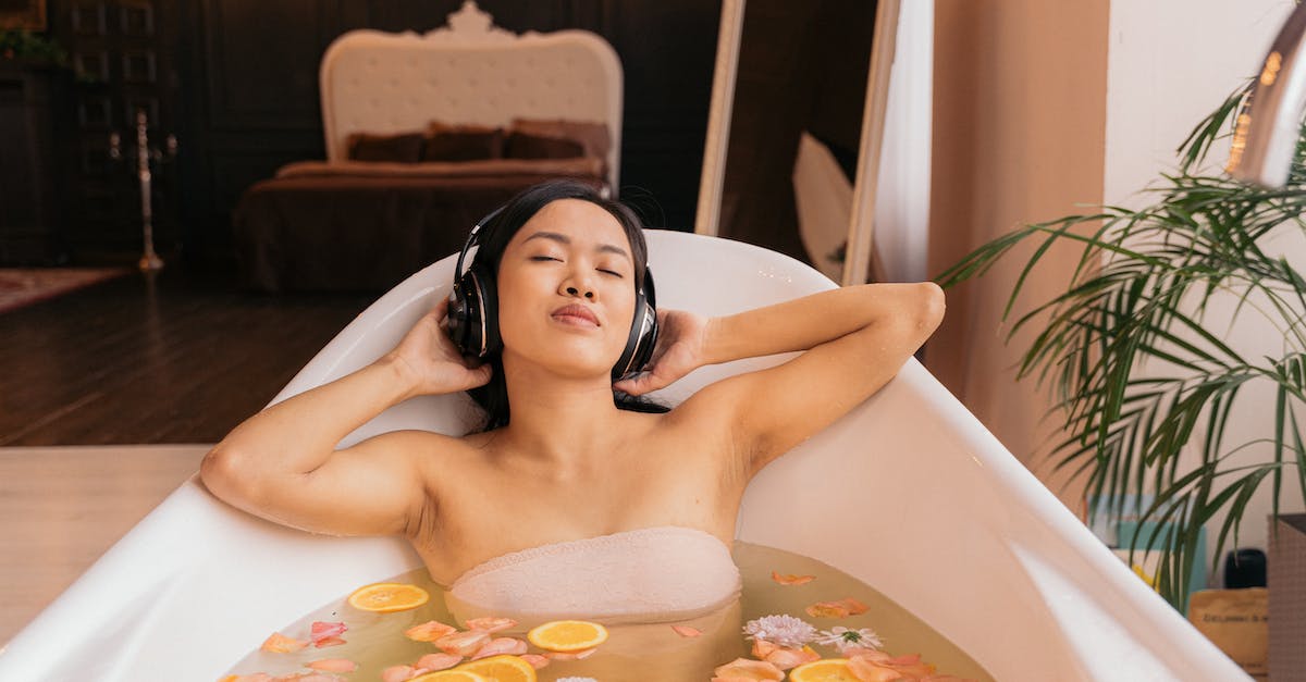 woman-taking-a-floral-bath-and-listening-to-music-on-headphones-3917919
