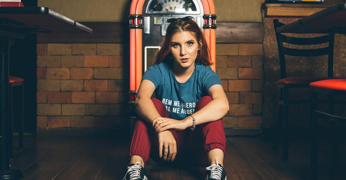 woman-wearing-blue-shirt-and-red-track-pants-sitting-beside-of-jukebox-9499450
