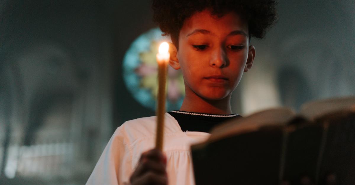 young-boy-reading-book-while-holding-a-candle-4290083