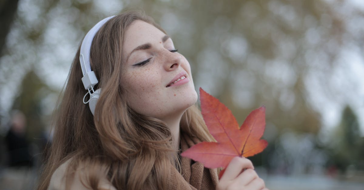 young-satisfied-woman-in-headphones-with-fresh-red-leaf-listening-to-music-with-pleasure-while-loung-1331886